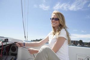 Frau zieht Seil im Segelboot foto