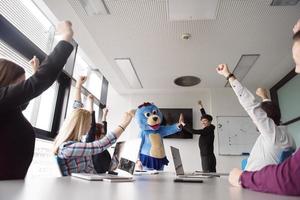 als bär verkleideter chef hat spaß mit geschäftsleuten im trendigen büro foto