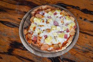 Hausgemachte italienische Pizza ist traditionelles Essen - Pizza-Käse-Scheibe auf Holztablett und serviert auf einem Holztisch foto