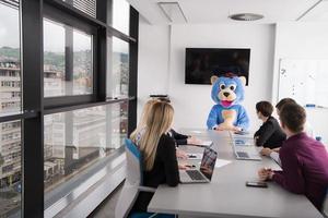 als bär verkleideter chef hat spaß mit geschäftsleuten im trendigen büro foto