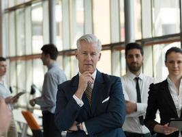 Portrait von Senior Geschäftsmann als Leader mit Personal im Hintergrund foto