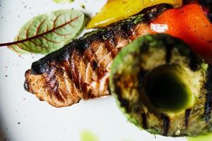 Gegrilltes Lachsfischfilet mit Gemüse und Avocado auf dem Teller, Nahaufnahme foto