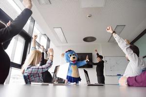 als bär verkleideter chef hat spaß mit geschäftsleuten im trendigen büro foto