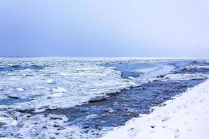 gefrorener fluss meer auf deich schnee eisschollen glattes eis. foto