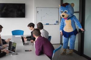 als bär verkleideter chef hat spaß mit geschäftsleuten im trendigen büro foto