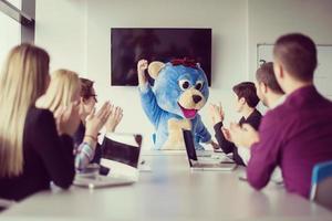 als bär verkleideter chef hat spaß mit geschäftsleuten im trendigen büro foto