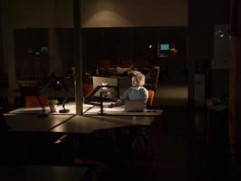 Mann, der im dunklen Büro am Computer arbeitet foto