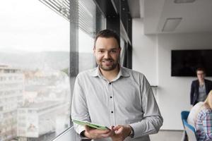 Geschäftsmann mit Tablet im Bürogebäude durch Fenster foto