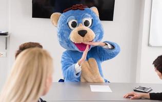 als bär verkleideter chef hat spaß mit geschäftsleuten im trendigen büro foto