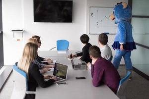 als bär verkleideter chef hat spaß mit geschäftsleuten im trendigen büro foto