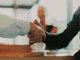 Geschäftsleute oder Anwälte, die sich die Hände schütteln und ein Treffen oder eine Verhandlung im sonnigen Büro beenden. foto