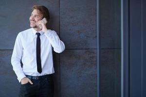 Startup-Geschäftsmann in einem weißen Hemd mit Krawatte mit Handy foto