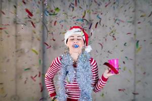 Geschäftsfrau, die einen roten Hut trägt und Partypfeife bläst foto