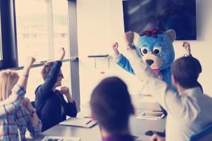 als bär verkleideter chef hat spaß mit geschäftsleuten im trendigen büro foto