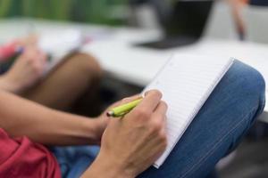 männlicher schüler, der sich im klassenzimmer notizen macht foto