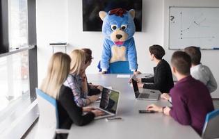 als bär verkleideter chef hat spaß mit geschäftsleuten im trendigen büro foto