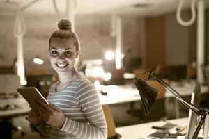 Frau, die im Nachtbüro an einem digitalen Tablet arbeitet foto