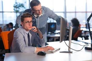 zwei geschäftsleute, die mit computer im büro arbeiten foto