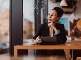 Latina-Frau, die in einer Pause von der Arbeit in einem Café sitzt foto