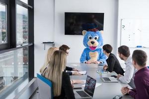 als bär verkleideter chef hat spaß mit geschäftsleuten im trendigen büro foto