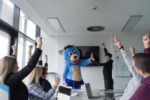 als bär verkleideter chef hat spaß mit geschäftsleuten im trendigen büro foto