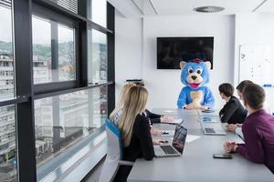 als bär verkleideter chef hat spaß mit geschäftsleuten im trendigen büro foto