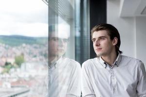 Junger Geschäftsmann im Startup-Büro am Fenster foto