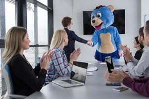 als bär verkleideter chef hat spaß mit geschäftsleuten im trendigen büro foto