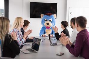 als bär verkleideter chef hat spaß mit geschäftsleuten im trendigen büro foto