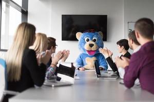 als bär verkleideter chef hat spaß mit geschäftsleuten im trendigen büro foto