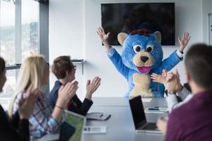 als bär verkleideter chef hat spaß mit geschäftsleuten im trendigen büro foto