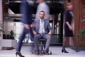 Geschäftsmann sitzt im Bürostuhl, Personengruppe vorbei foto