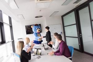 als bär verkleideter chef hat spaß mit geschäftsleuten im trendigen büro foto