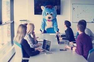 als bär verkleideter chef hat spaß mit geschäftsleuten im trendigen büro foto