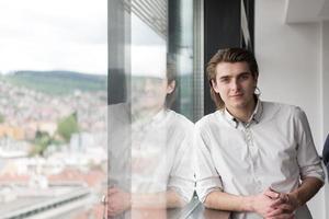 Junger Geschäftsmann im Startup-Büro am Fenster foto