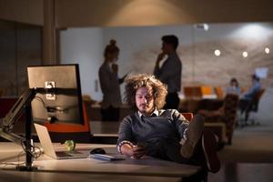 Geschäftsmann sitzt mit Beinen auf dem Schreibtisch im Büro foto