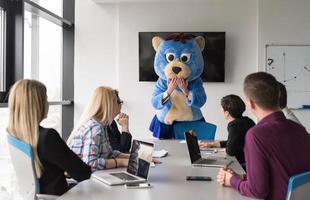 als bär verkleideter chef hat spaß mit geschäftsleuten im trendigen büro foto