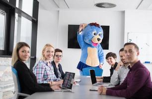 als bär verkleideter chef hat spaß mit geschäftsleuten im trendigen büro foto