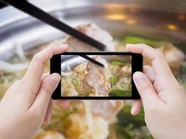 frau, die foto von sukiyaki shabu shabu macht