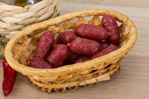 Mini-Salami in einem Korb auf Holzhintergrund foto