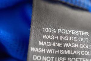 schwarze Wäschepflege Waschanleitung Kleideretikett auf blauem Jersey-Polyester-Sporthemd foto