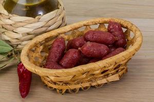 Mini-Salami in einem Korb auf Holzhintergrund foto