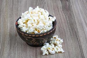 Popcorn in einer Schüssel auf hölzernem Hintergrund foto