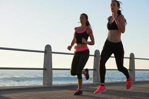 zwei weibliche Athleten, die im Freien Fitness-Tracker-Gerät laufen foto