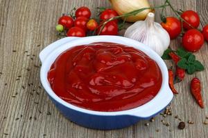 Tomatenketchup in einer Schüssel auf Holzhintergrund foto