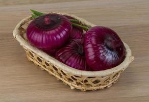 violette Zwiebel in einem Korb auf Holzhintergrund foto