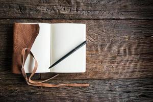 Ein geöffnetes Tagebuch aus Leder mit Leerzeichen auf dem Holztisch. das Bildungs- und Lernkonzept. foto