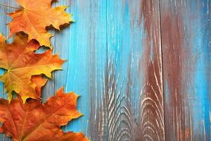 Rahmen aus bunten Herbstblättern auf blauem und braunem Holzhintergrund foto