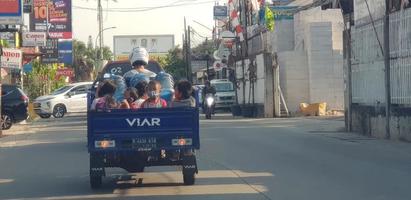 west java im april 2019. eine gruppe von kindern fährt auf einem dreirad, hinter dem sich ein schiff befindet. foto