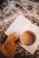 Person hält Becher mit offenem Buch foto